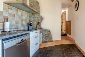 a kitchen with white cabinets and a stone wall at 1 Bed in Bideford oc-labdr in Woolfardisworthy