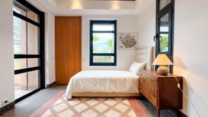 a bedroom with a bed and a dresser and windows at Villa TIGMIZEN - 10CH - Piscine chauffée et Spa - Marrakech in El Aouina