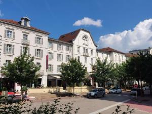 a large white building with cars parked in front of it at Hôtel Mercure Vittel in Vittel