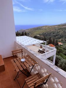 a balcony with two wooden chairs and a table at Art & Motion Union - Guest Room 4 in Andros