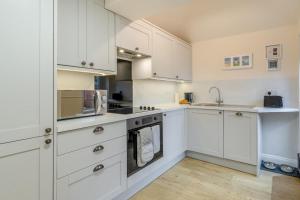 a white kitchen with white cabinets and a sink at 1 Bed in Lytham St. Annes oc-86044 in Saint Annes on the Sea +15 photos