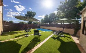 a yard with two chairs and two umbrellas and a pool at La Casita de Lucia in Trescasas