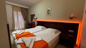 a hotel room with two beds and an orange blanket at Nefeli Boutique Hotel in Agios Kirykos