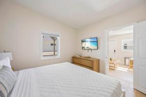 a white bedroom with a bed and a television at Anchor House in Cocoa Beach