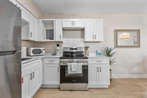 a kitchen with white cabinets and a stove top oven at Breakwater Bungalow in Cocoa Beach