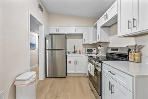 a kitchen with white cabinets and a stainless steel refrigerator at Breakwater Bungalow in Cocoa Beach +6 photos