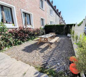 a picnic table and bench in a yard next to a building at Le Maluthina Maison Familiale au Hourdel entre Mer & Nature in Cayeux-sur-Mer