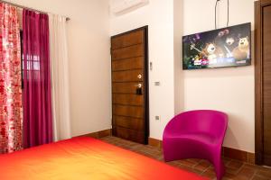 a bedroom with a purple chair and a tv at Lilium B&B Villa Patrizia - Con piscina e parcheggio by Mamo Florence in Itri