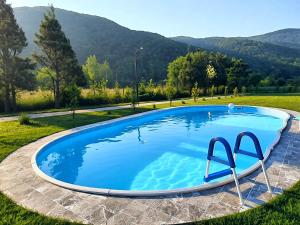 a large blue swimming pool in a field with mountains at Котедж в ГОРАХ in Solochyn