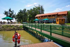 a boat is parked next to a river with a restaurant at Zserbó lak in Kisapostag