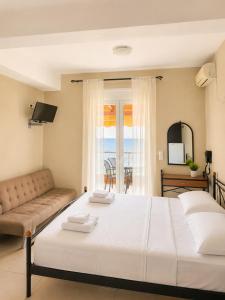 a bedroom with a large white bed and a couch at PNOÉ rooms in Ilia