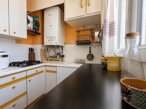 a kitchen with white cabinets and a black counter top at Charmant appartement au cœur de Paris in Paris +12 photos
