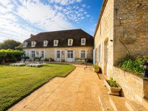 a large brick building with chairs in a yard at Manoir Jorama - ancien musée de Joséphine Baker in Castelnaud La Chapelle