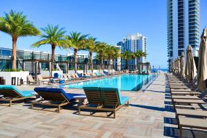 a swimming pool with lounge chairs and palm trees at Steps from the Beach - Amazing Views in Hollywood