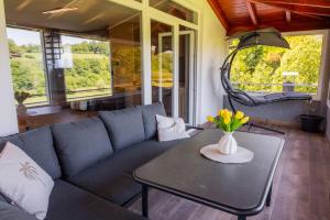a living room with a couch and a table with flowers at Korana River Retreat with Sauna & Jacuzzi and View by Destination GREEN Croatia in Barilović