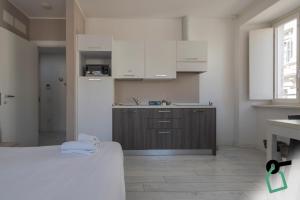 a kitchen with white cabinets and a bed in a room at Hotiday Trieste Corso Italia in Trieste
