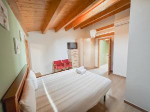 a bedroom with a white bed and a red chair at Apartaments Ca L'Albert in La Pobla de Segur