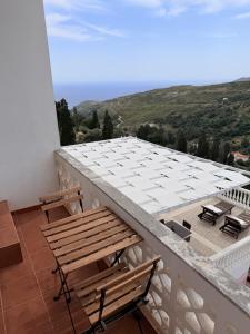 a balcony with a wooden bench and a table on a roof at Art & Motion Union - Guest Room 5 in Andros +7 photos