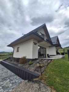 a small white house with a black roof at Domki nad Borem in Małe Ciche