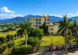 a building with palm trees and mountains in the background at Nature View Retreat in Rishīkesh
