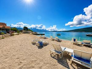 a sandy beach with chairs and a boat in the water at Villa Magnetic in Baošići