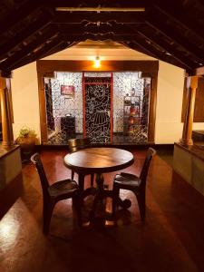 a table and chairs in a room with a wall at Padmalayam Heritage Villa in Mānantoddy
