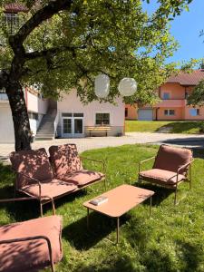 three chairs and a table in the grass under a tree at Apartments Gorje Hideaway in Spodnje Gorje