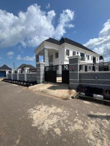 a white house with a fence in front of it at House One Apartment in Akure