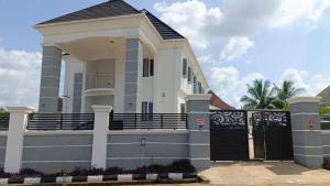 a large white house with a black gate at House One Apartment in Akure