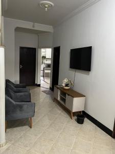 a living room with a couch and a tv on a wall at Quarto para viajantes in Montes Claros