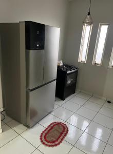 a kitchen with a refrigerator and a rug on the floor at Quarto para viajantes in Montes Claros
