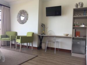 a living room with a table and green chairs at Classical View Guesthouse in Mossel Bay