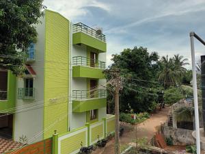 a yellow building with green balconies next to a street at FM Villa Auroville in Pondicherry