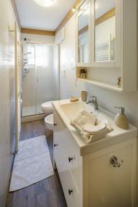 a white bathroom with a sink and a toilet at CiasaToa in Cortina dʼAmpezzo +11 photos