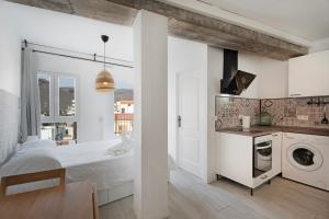 a white kitchen with a bed and a washing machine at Apartamento La Pista Sur in San Sebastián de la Gomera