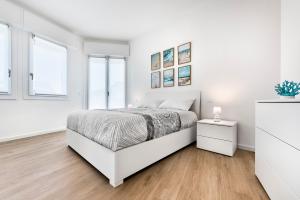a white bedroom with a bed and two windows at Sand Beach House - Host Solution in Cavallino-Treporti