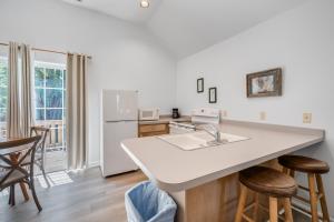 a kitchen with a sink and a counter with stools at Chris Cottage 3 in Chincoteague