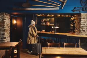 a woman with a suitcase standing at a bar at Inn at Port nan Gael in Pennyghael