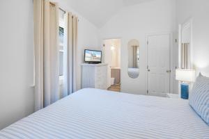 a white bedroom with a bed and a television at Chris Cottage 3 in Chincoteague +18 photos