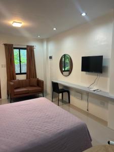 a bedroom with a bed and a tv and a couch at Residencia de Azucena in Tacloban