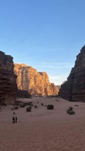 two people walking in the desert between two cliffs at وادي رم in Disah