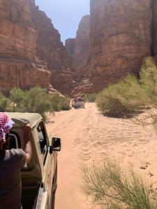 a person looking out the window of a jeep driving through a canyon at وادي رم in Disah