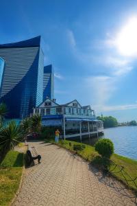 a building next to the water with a person standing on a bench at The Infinity Panorama Batumi in Batumi