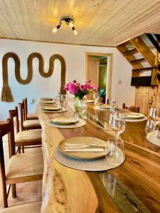 a dining room with a long table with glasses and flowers at Casa Rogin in Buhalniţa