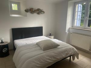 a bedroom with a white bed with a black headboard at Appartement calme et serein in Vals-près-le-Puy