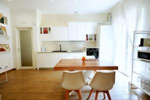 a kitchen with white cabinets and a wooden table and chairs at Casa Federica by MOH in Grottaglie
