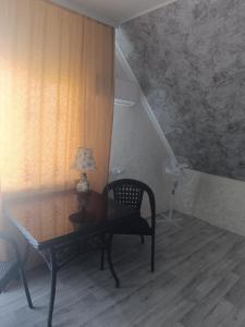 a room with a table and a chair with a lamp at 'Белый дом' in Balqash