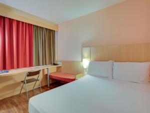 a hotel room with a large bed and a desk at ibis Vitoria Praia de Camburi in Vitória +105 photos