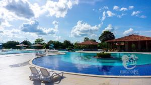 a large swimming pool at a resort with chairs at Ground floor flat with two suites (up to 8 people) at Canarius Resort in Gravatá in Gravatá