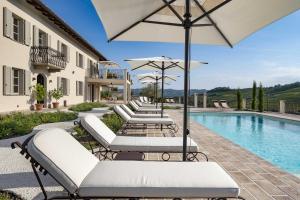 a resort pool with white lounge chairs and an umbrella at Casa di Sofia in Calosso